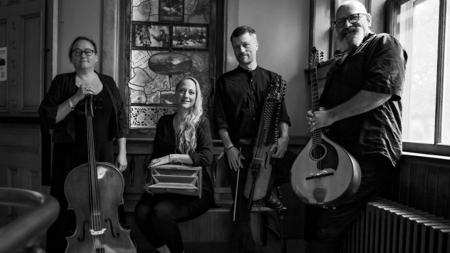 Black-and-white photo of four musicians posing with their instruments.
