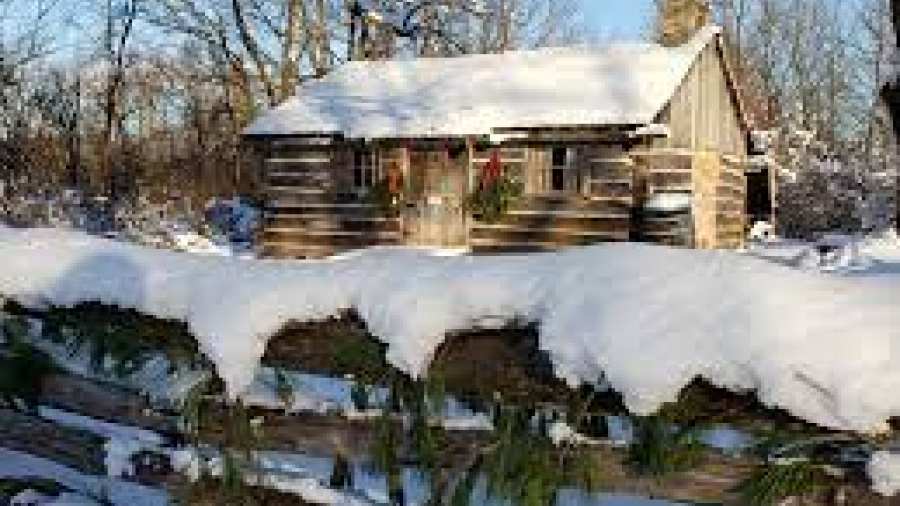 Fanshawe pioneer village picture of a log cabin covered in show with Christmas decorations hanging outside in the daylight