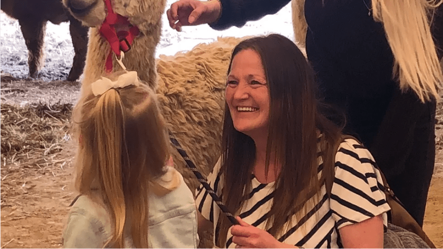 Woman and young girl interact with an alpaca at Timbuktu Alpaca Farm and Agri-Tourism Farm