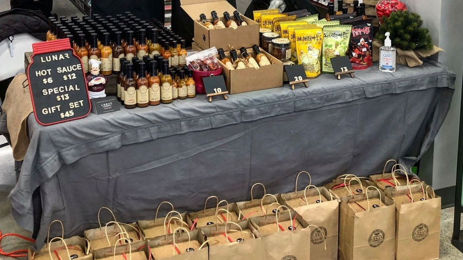 picture of Lunar hot sauce at a market with their products displayed on a table 