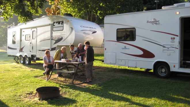 A family having a picnic with RVs in the back 