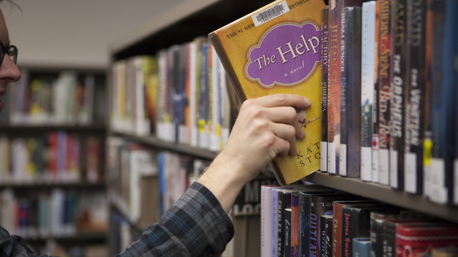 hand pulling out a book from shelf 