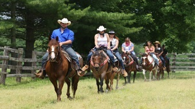 people riding horses through the stable at texas longhorn ranch 