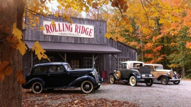The storefront of rolling ridge in the fall, with classic cars parked out front