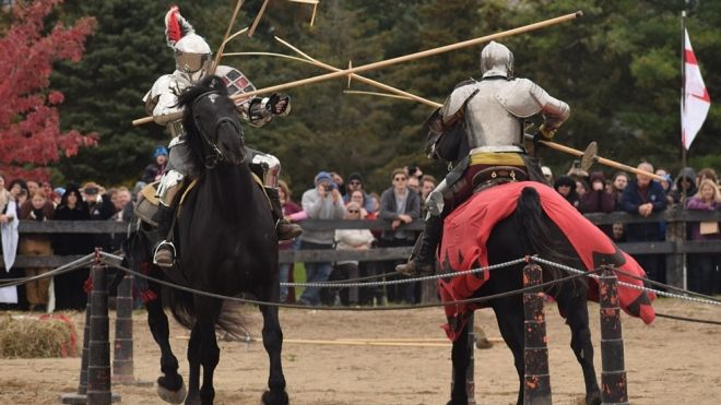 Two men in medival jousting gear poke eachother with sticks