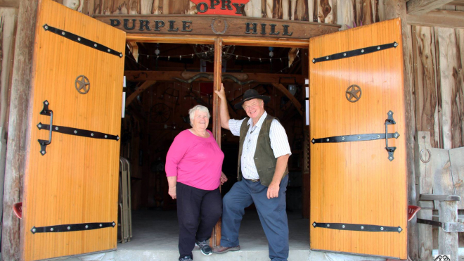 purple hill entrance way with the two owners, a man and woman smiling for the camera 