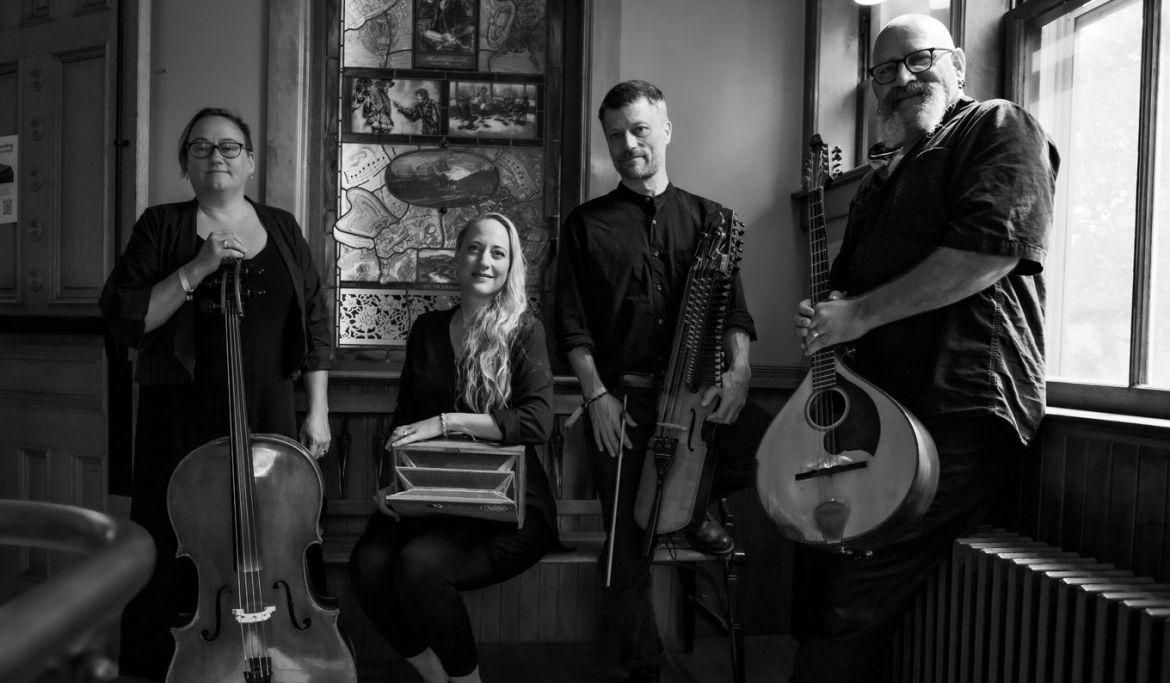 Black-and-white photo of four musicians posing with their instruments.