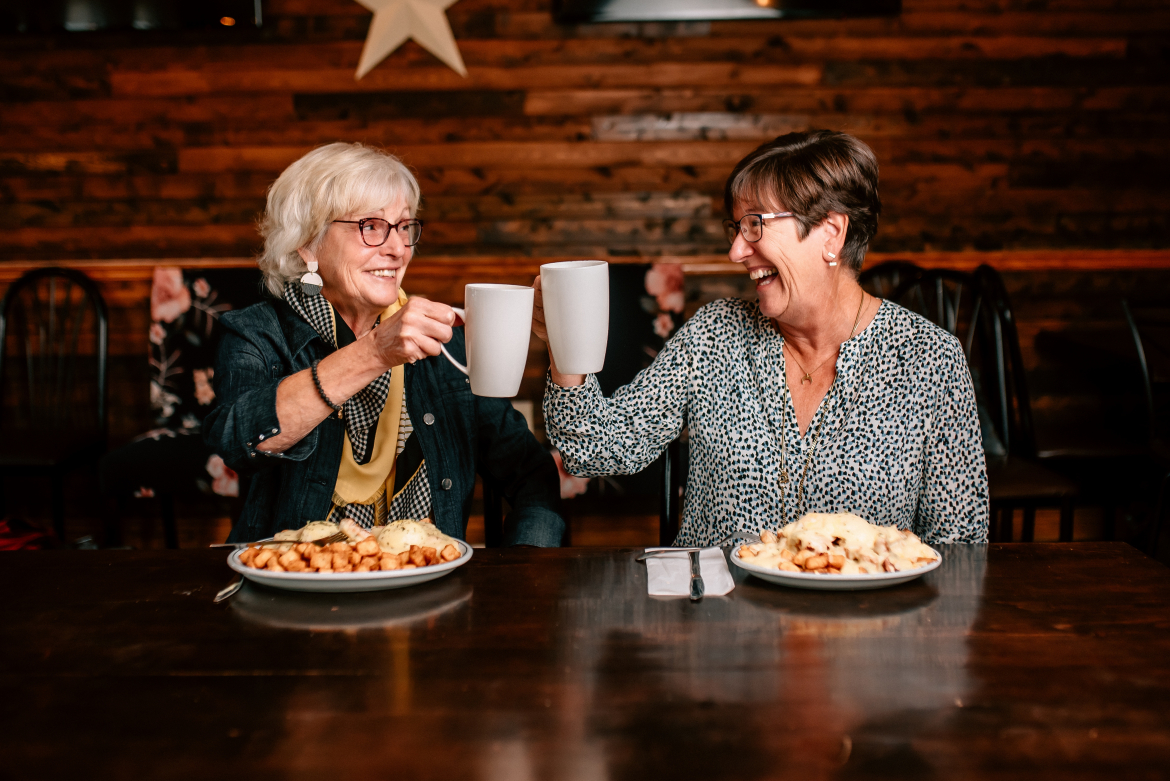 two ladies clinking coffee mugs