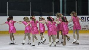 a group of young girls figure skating in pink outfits