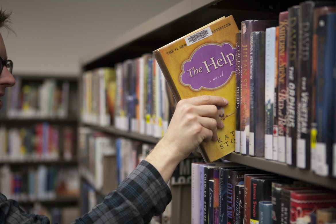 hand pulling out a book from shelf 