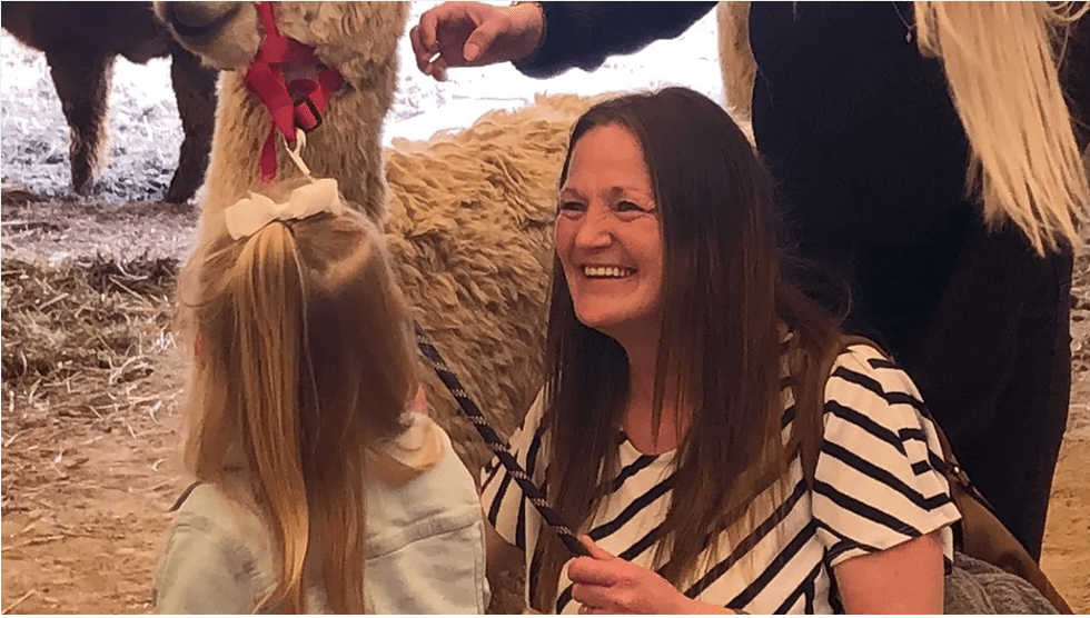 Woman and young girl interact with an alpaca at Timbuktu Alpaca Farm and Agri-Tourism Farm