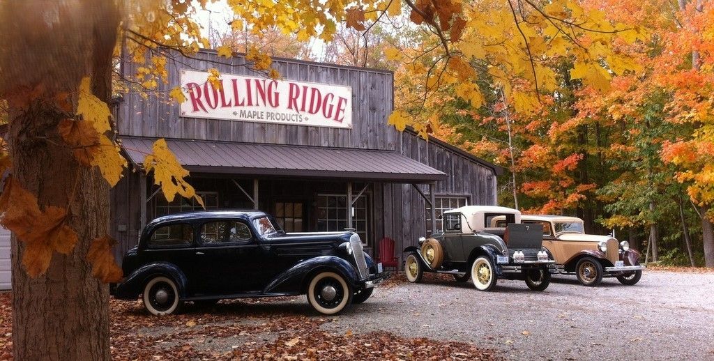 The storefront of rolling ridge in the fall, with classic cars parked out front