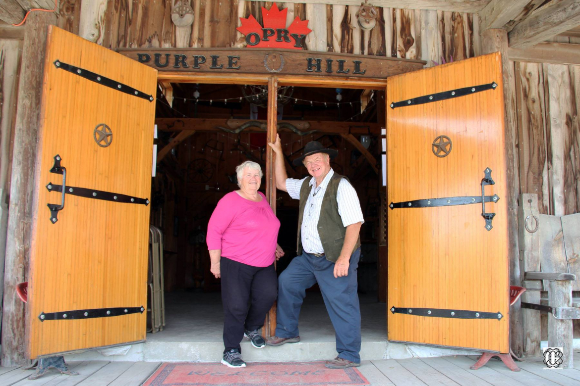 purple hill entrance way with the two owners, a man and woman smiling for the camera